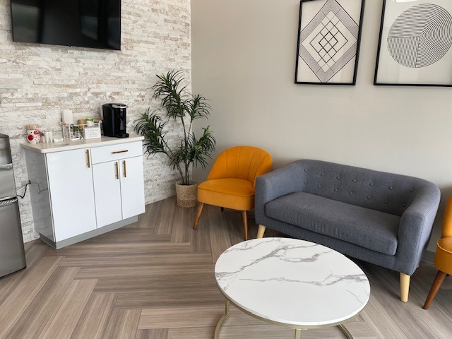 Polaris Dentistry waiting room with a gray sofa, yellow chairs, a coffee table, and a beverage station