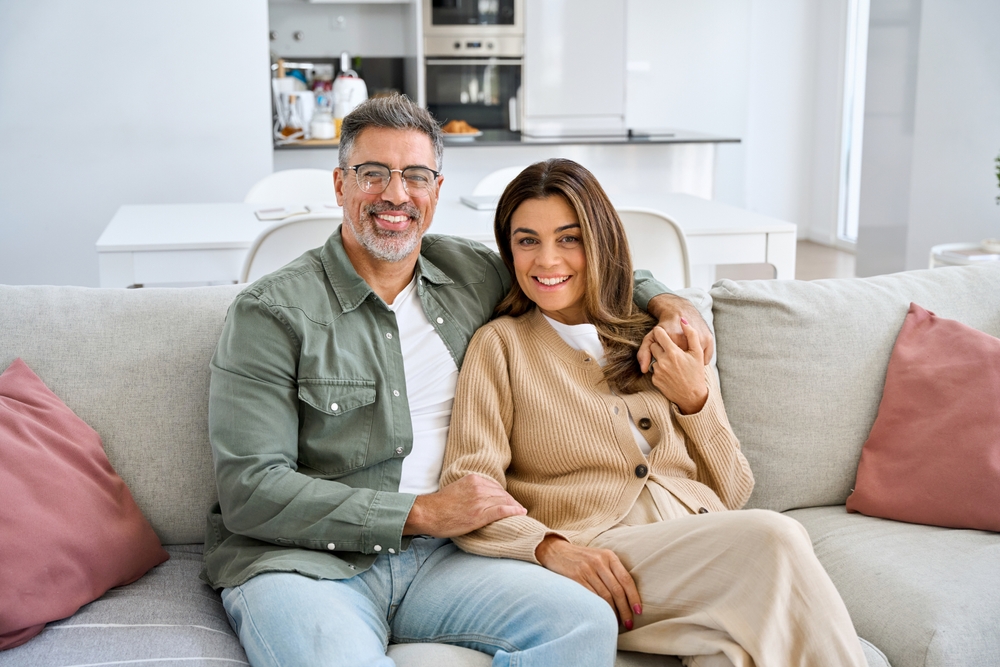 A smiling couple sitting together on a sofa at home